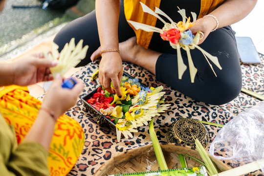 Balinese women preparing Canang sari with colorful flowers