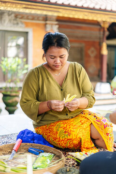 Balinese woman preparing Canang sari, traditional offering in Bali