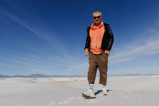 A young guy walks on the sand in the desert