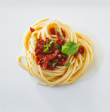 spaghetti topped with sun dried tomatoes and fresh basil garnishes
