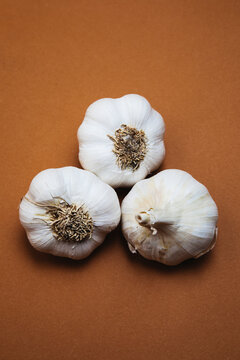 Three Garlic Bulbs on Brown Surface