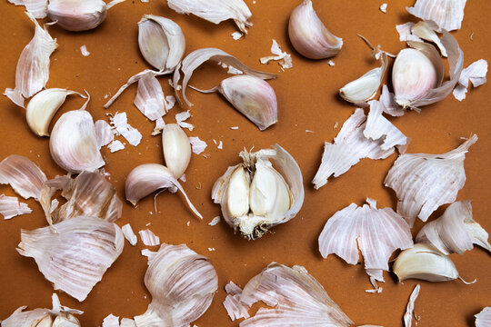 Garlic Cloves and Peels on Brown Background