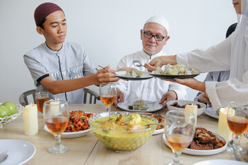 Portrait Of Young Muslim Female Sharing Food To His Brother During Eid Al Fitri