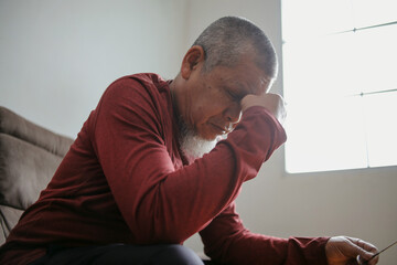 Senior Man Suffering From Headache And Massaging Nose Bridge At Home