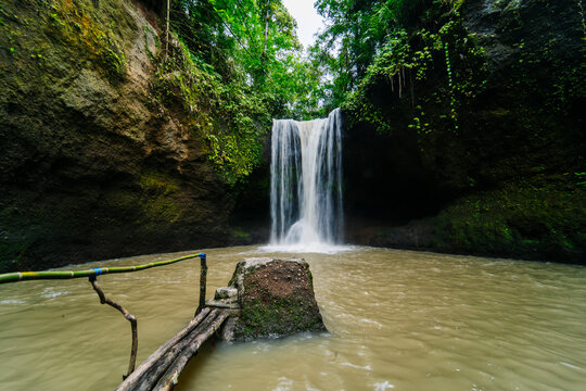Suwat Waterfall cascading into brown water pool in Bali, Indonesia