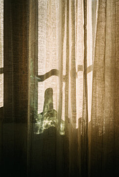 Film photography of soft sunlight filtering through linen curtains