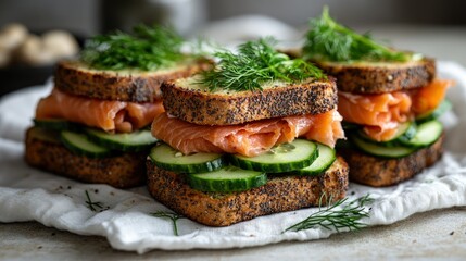 Fresh salmon cucumber sandwiches.  Three delicious looking sandwiches with slices of smoked salmon and cucumber on seeded bread.  Garnished with fresh dill