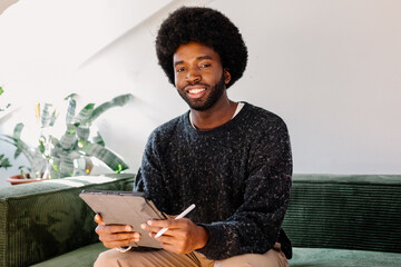 Diverse man smiling at camera while filling out a job application