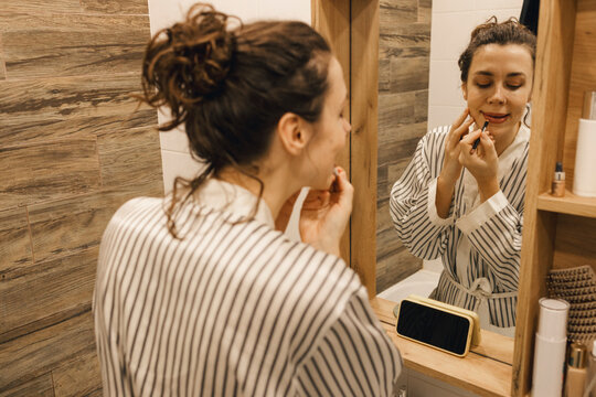 Portrait of a woman looking to video tutorial to put on makeup
