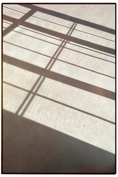 Concrete floor with long shadows of a window frame during a summer day