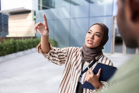 Serious colleagues looking up while discussing over digital tablet