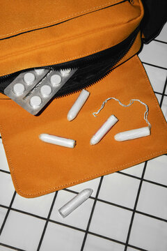 Feminine hygiene products and medication from a vibrant orange bag.