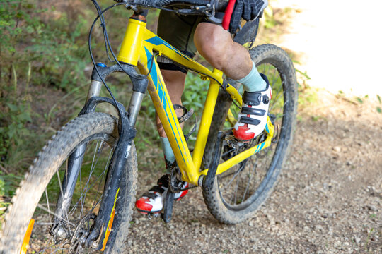 The legs of an anonymous mature cyclist pedaling on a dirt road