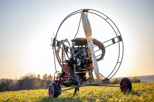 Paragliding machine for paragliding flights on green grass against the bright sun. Preparing paralet with a gasoline engine for flights. Extreme sports
