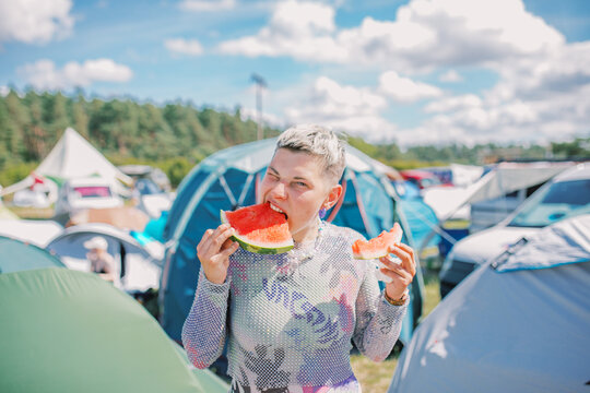 Non-Binary Individual Eating Watermelon at a Festival