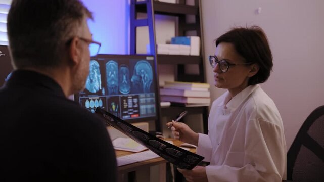 Patient MRI scan is analyzed by doctors with patient to diagnose brain conditions and determine appropriate treatment. Medical hospital