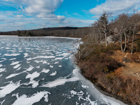 Frozen Lake with Bare Trees and Rocky Shoreline