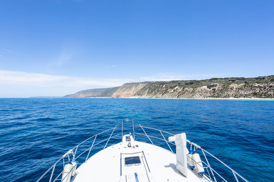Bow of a boat cruising past an island. Blue sky with copy space.