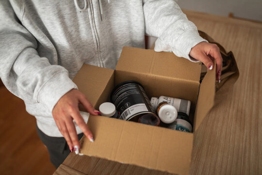 woman at home opening order box for supplements and vitamins