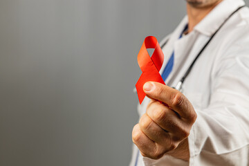 Healthcare professional holds red ribbon for HIV awareness campaign