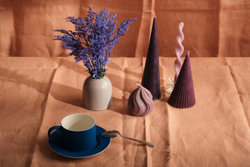 purple candle composition with flowers and natural pink textiles