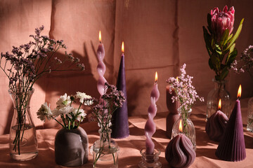 purple candle composition with flowers and natural pink textiles