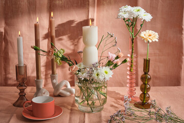 candle composition with flowers and natural pink textiles