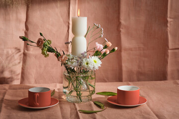 candle composition with flowers and natural textiles, orange cups, tea ceremony