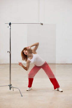 Woman behind plexiglass in dance pose