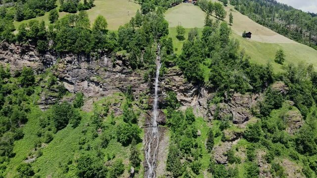 Scenic aerial view of Fallbach Waterfall cascading down verdant alpine landscape