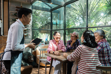 Restaurant eatery shop, Asian senior women having fun searching menus from tablet computer learning to order food by modern application, elderly pension females happy friendly with wireless technology