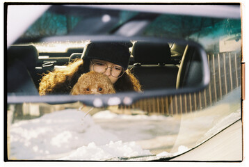A girl enjoys precious moments with small dog in car 