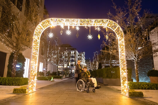 Happy disabled teeneger and mother in an arch of New Year's garlands