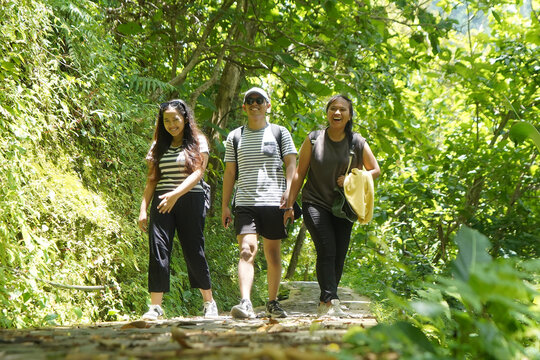 group of happy young asian indonesian people walking together on the walk path in the park