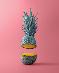 Visually striking floating pineapple with metallic peel and a drip of juice in a creative surreal composition on pink backdrop.