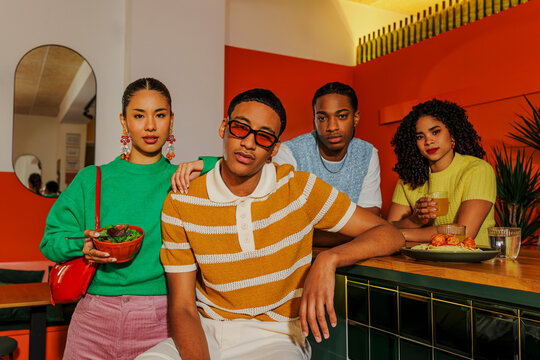 Group of diverse friends enjoying meal together in modern restaurant