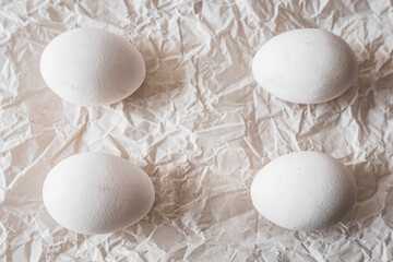 White eggs placed on crumpled paper, creating a minimalist and organic composition. Soft natural light enhances textures, making it ideal for Easter, food photography, and rustic backgrounds