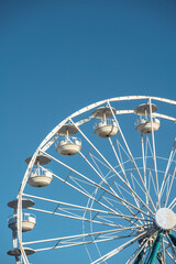Ferris wheel towering against a clear blue sky during a sunny day. vertical.