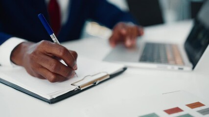 Workplace of successful businessman or office worker, closeup of hands on table. Black man working with modern laptop and writing on paper, financial analyst reading economic report and making notes