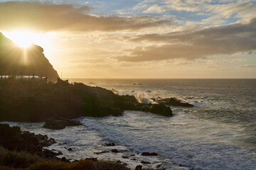 Obraz premium Golden sunset over a rugged volcanic coastline........