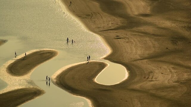 People walking on sandbanks at low tide  
