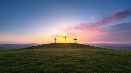 Obraz premium Three Christian crosses stand solemnly on a grassy hilltop their silhouettes framed against a breathtaking sunset sky filled with warm hues of orange pink and purple