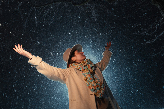 Woman Gazing Up with Arms Open in Snowfall