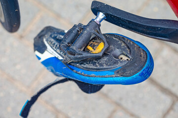 Road Cycling and Sport Concept. Dirty Cycling Professional Carbon Shoes with Cleats Hanged On Road...