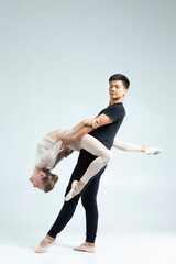 Couple of Asian Man and Caucasian Woman Performing As Ballet Dancers On Grey in Studio During Suppots As Classical Dance And Choreography as Ballet Dance Concepts. © danmorgan12