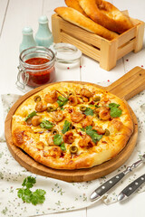 Italian pizza with shrimps and seafood on a wooden board.