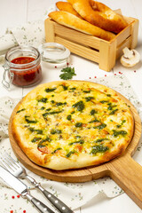 Italian pizza with cheese and pesto sauce on a wooden board.