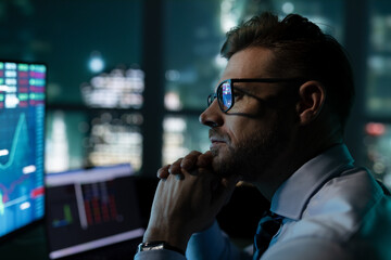 Thoughtful stock market analyst working in front of skyline window 