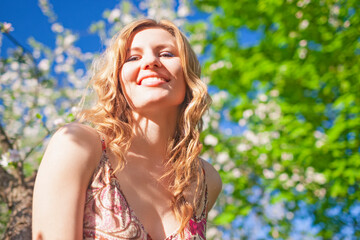 Naklejka premium Travel and Vacation Ideas. Portrait of Relaxing Winsome Alluring Sensual Caucasian Blond Female In Floral Dress Posing in Summer Park Against Trees.
