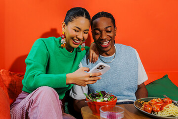 Couple laughing and using smartphone in modern restaurant
